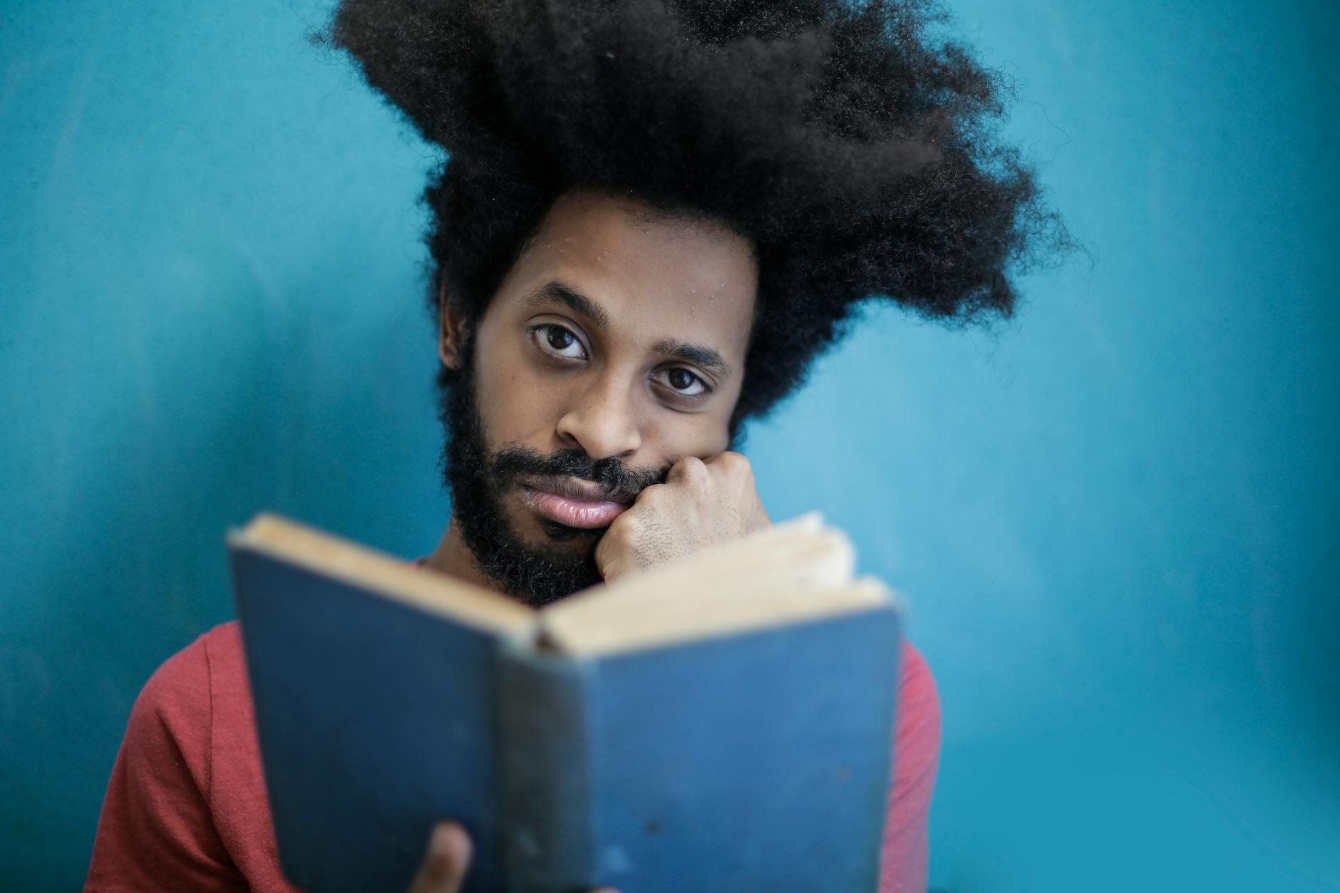 man in red shirt holding blue book